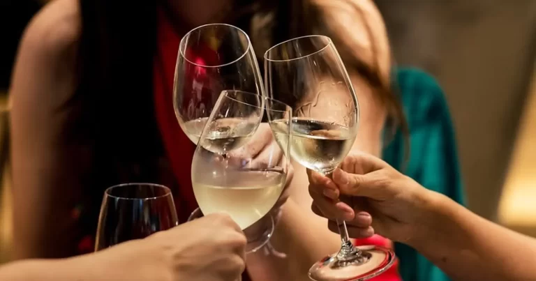 Prieteni ciocnind pahare cu vin și șpriț într-un local
