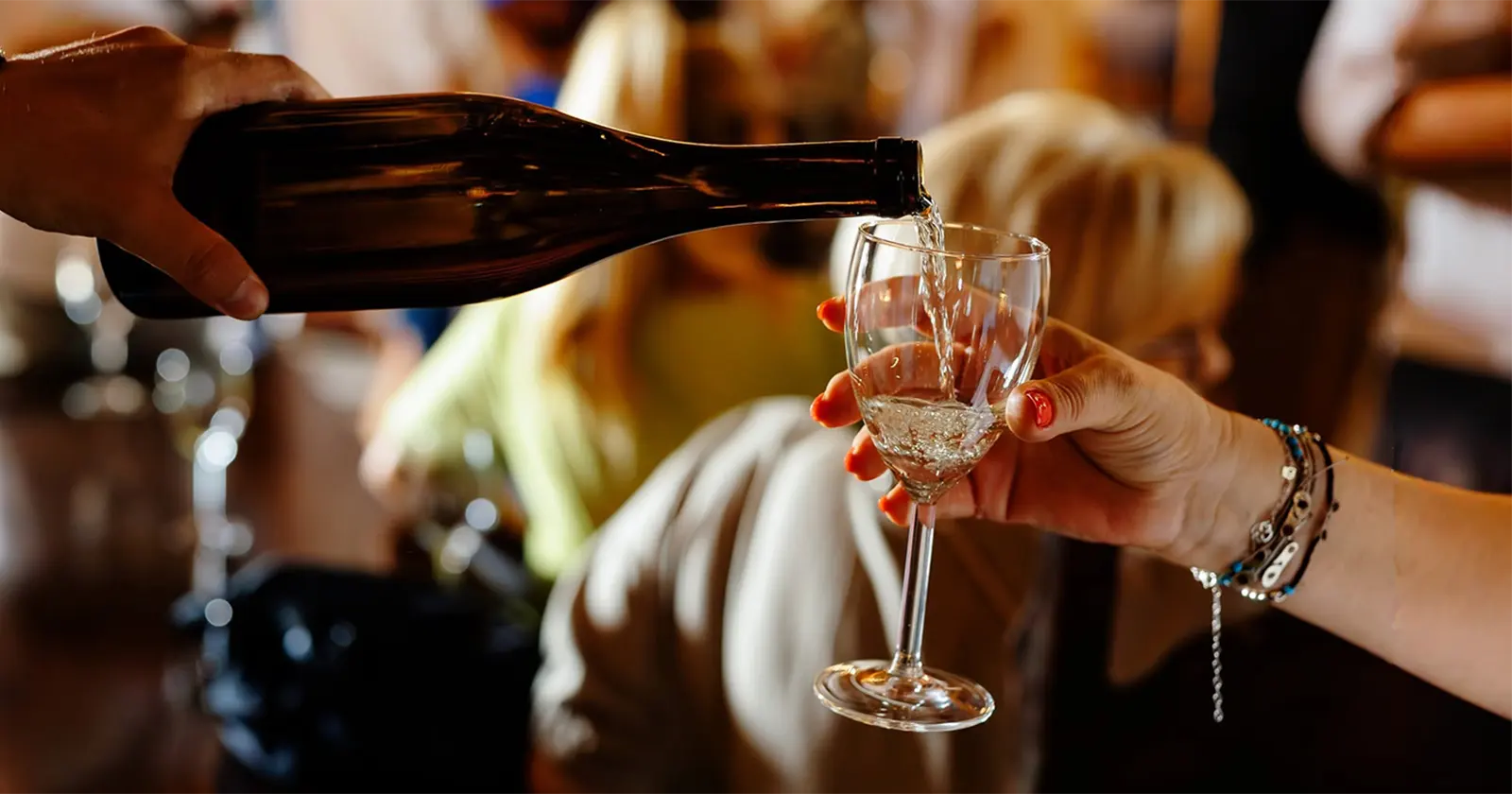 Vin alb turnat într-un pahar într-un local animat