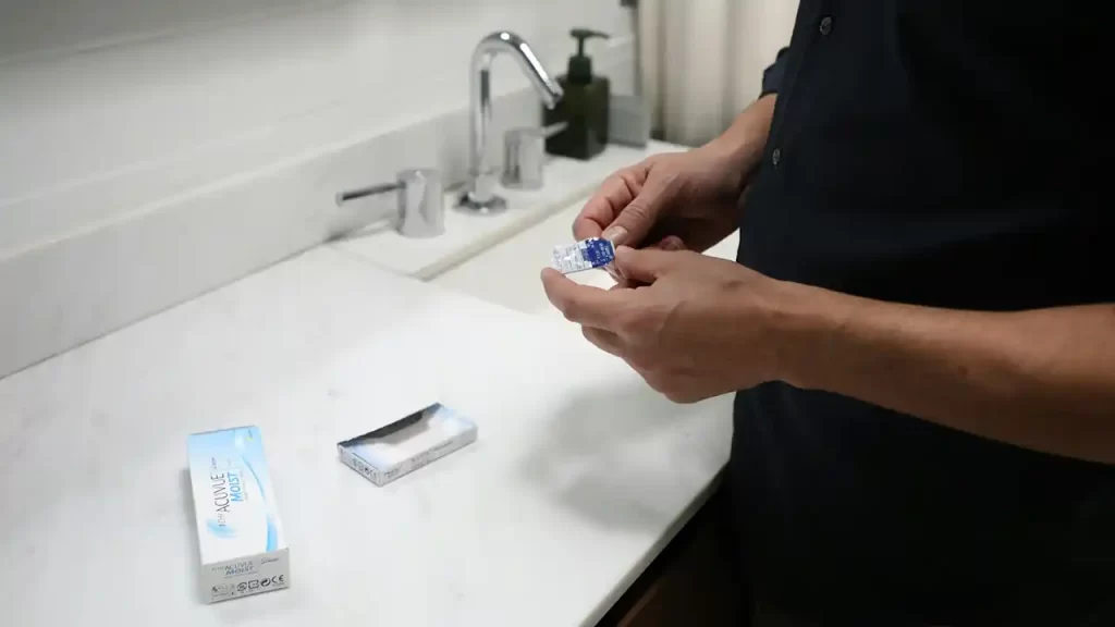 Imagine cu un bărbat care ține în mână un set de lentile de contact