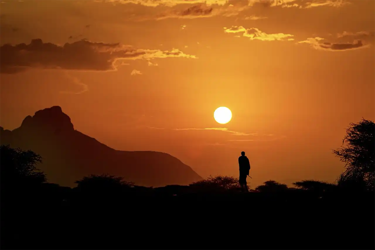 Conturul Munților Ndoto apare odată cu răsăritul soarelui. Un bătr&acirc;n Samburu completează peisajul idilic. Kenya, 2026 (foto Andrei Mihalca)