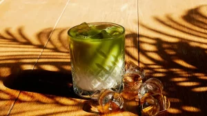 un pahar de băutură matcha cu lapte și cuburi de gheata