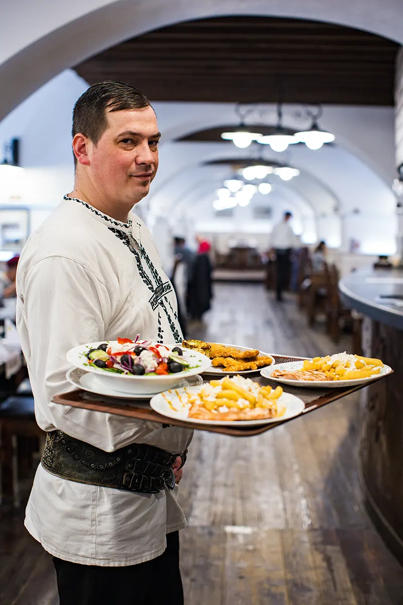 Ospătar Sergiana cu tava plină în restaurantul din Brașov