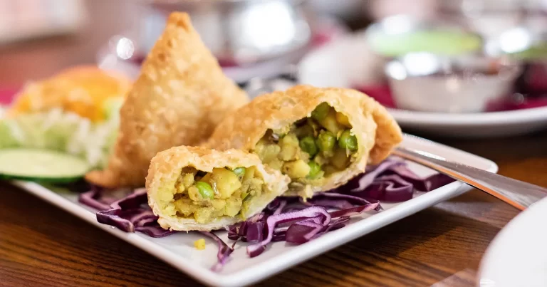 Samosa crocantă cu umplutură de cartofi și mazăre, servită cu sosuri la un picnic de vară