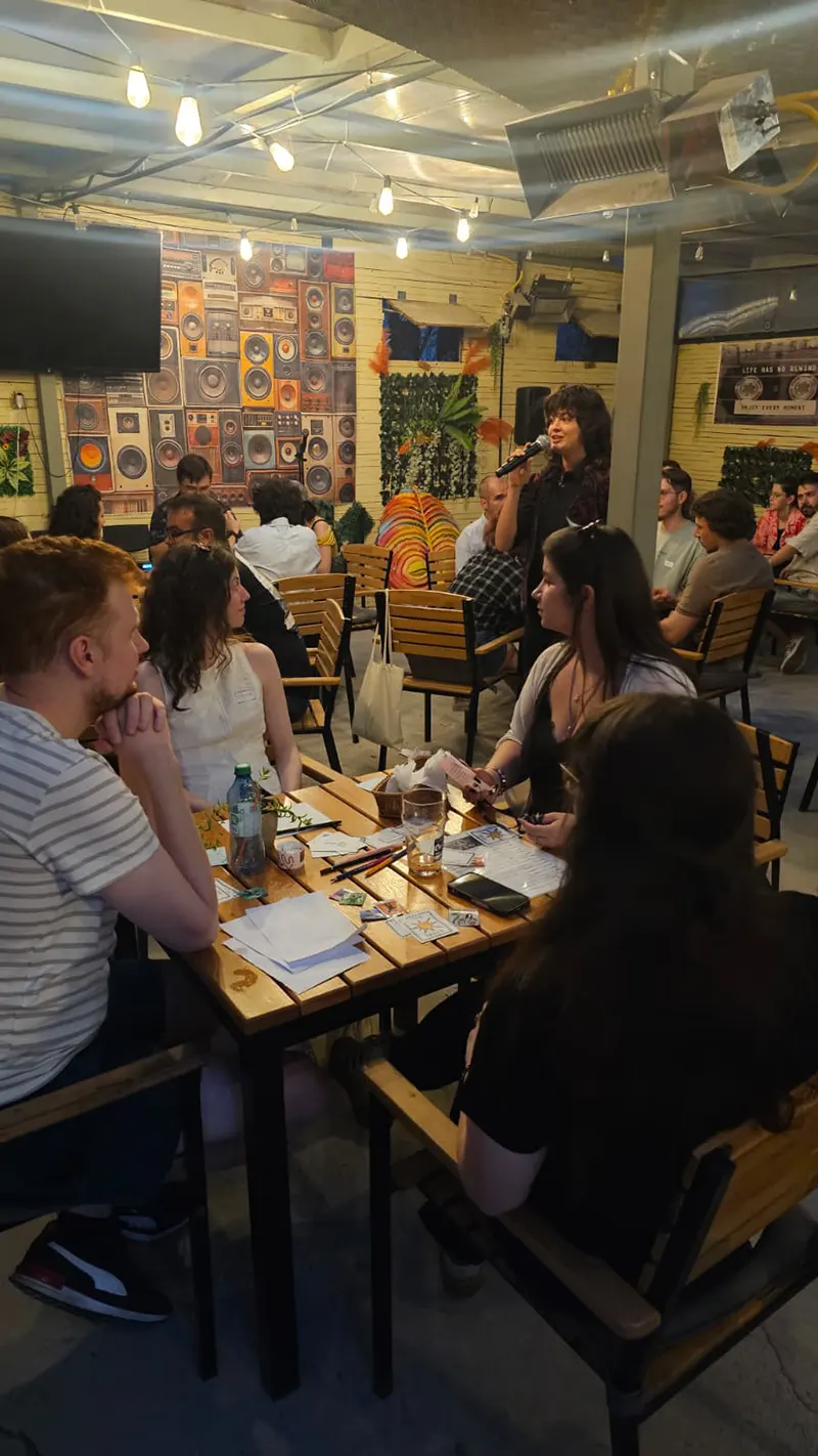Participanți discutând la mesele unui eveniment Flow Social
