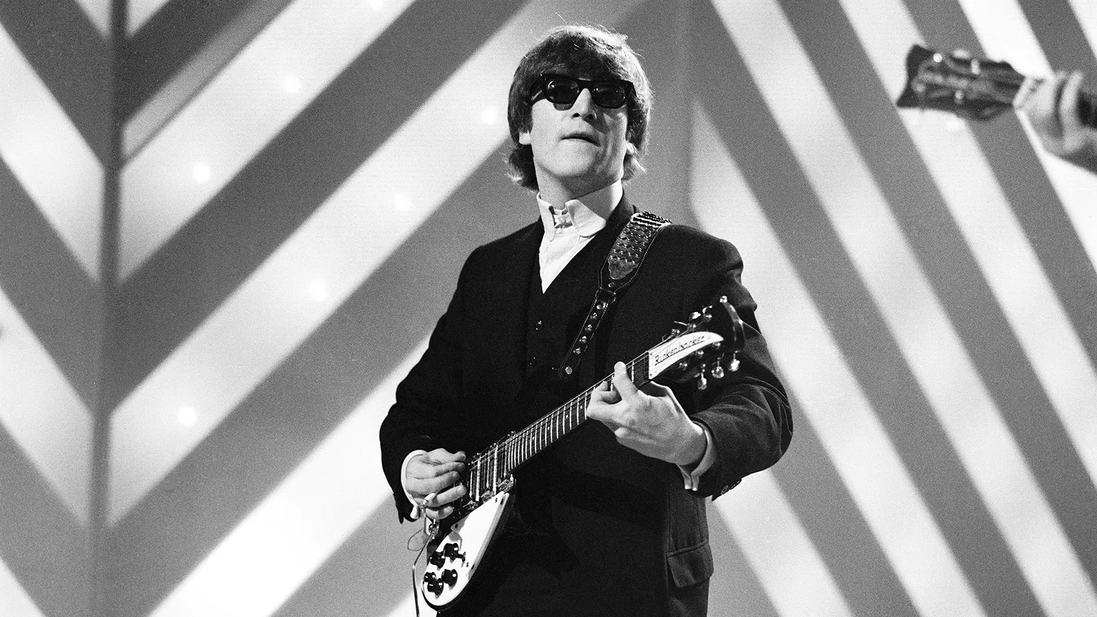 John Lennon cântând la chitară pe scenă în perioada Beatles