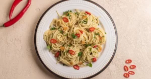 combinații neobișnuite de paste - Spaghetti cu usturoi, ardei iute și verdeață, servite într-o farfurie albă
