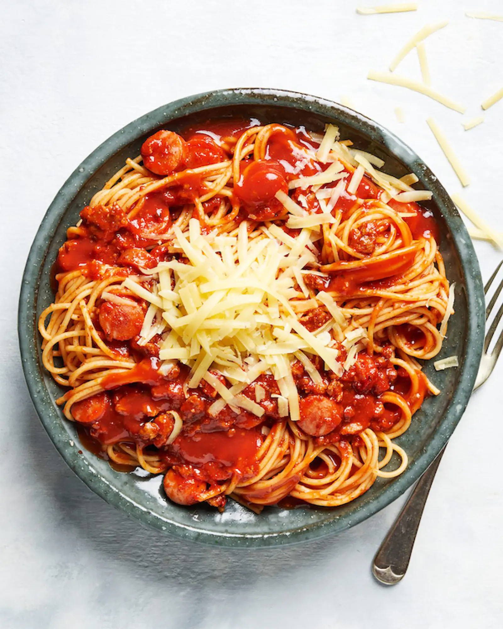 Spaghetti filipineze cu sos roșu, felii de crenvurști și brânză rasă