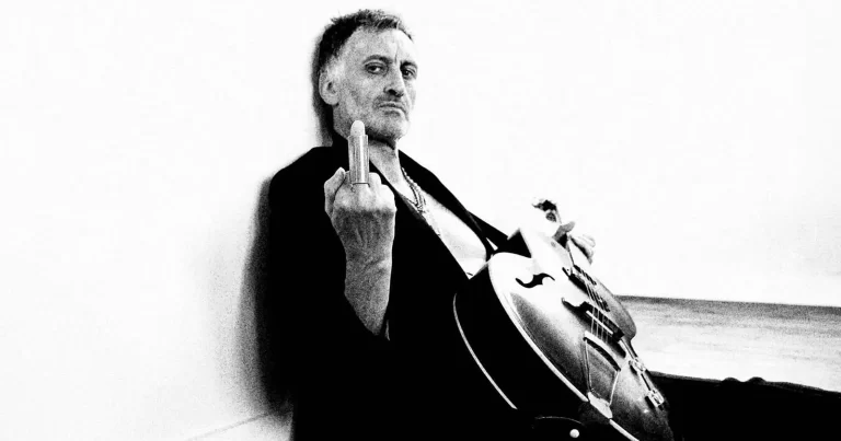 Simon Boswell într-un portret alb-negru, alături de un violoncel